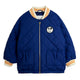 A navy blue quilted bomber jacket with a gold zipper, featuring a circular Mickey Mouse patch on the left chest, striped collar and cuffs, and front patch pockets, shown against a plain white background.