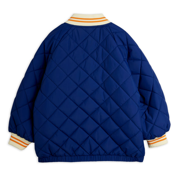 A royal blue quilted bomber jacket shown from the back, featuring diamond-quilted stitching, a cream ribbed collar and cuffs with orange stripes, and an elasticated hem.