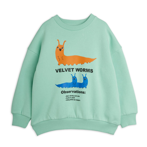 A mint green crewneck sweatshirt featuring a graphic print of an orange velvet worm and a blue pair of velvet worms with text reading 'VELVET WORMS' and 'Observations:'.
