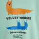 A close-up of a mint green graphic print featuring cartoon worm illustrations and text reading 'VELVET WORMS' and 'Observations:'.
