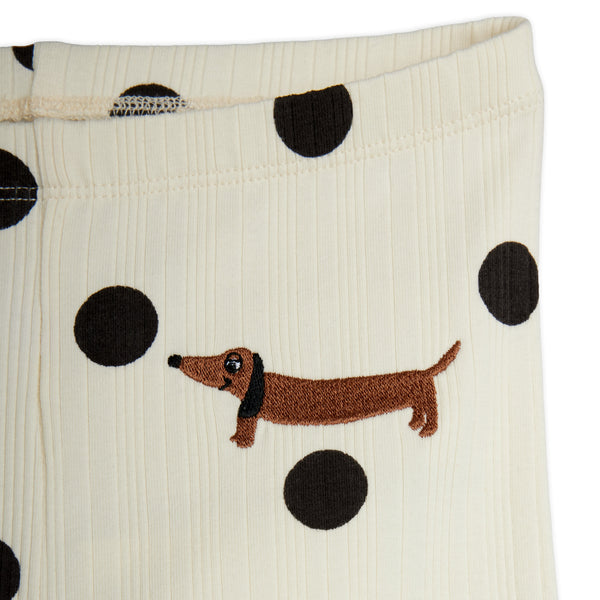 Close-up of cream ribbed fabric with large black polka dots and an embroidered brown dachshund on the front.