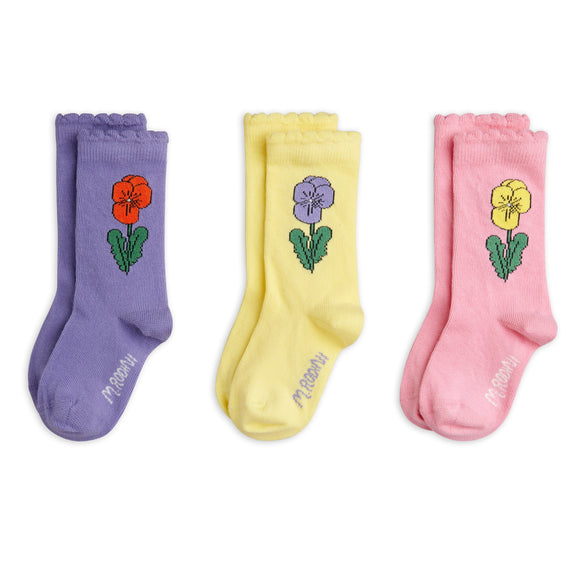 Three pairs of crew socks in purple, yellow, and pink, each featuring an embroidered flower with green leaves and the brand name 'princess' printed near the foot.