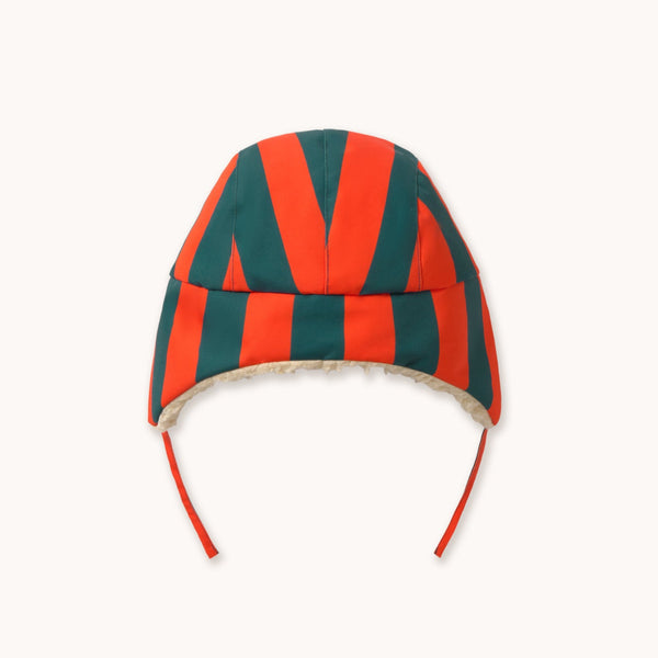 A chapka hat featuring bold red and dark green striped chevron patterns, with a beige fleece lining and red ear flaps, shown against a plain off-white background.