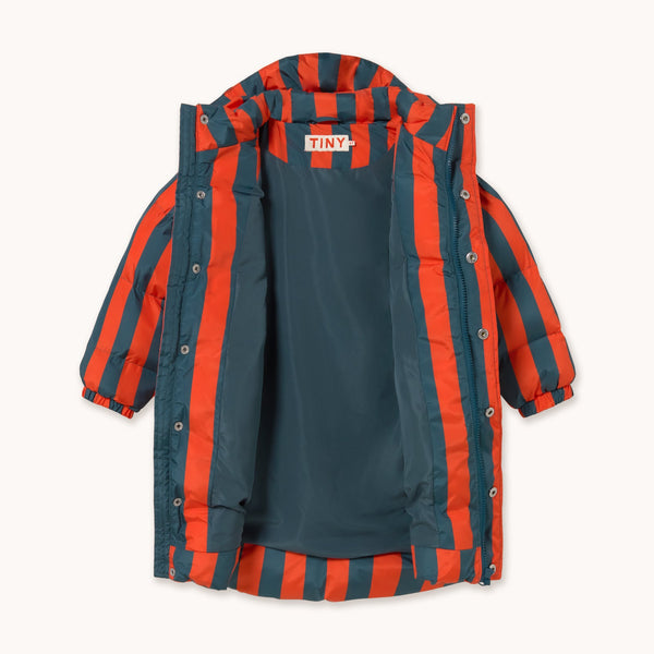 A children's puffer jacket with vertical orange-red and navy blue stripes, shown flat against a light cream background. The brand name 'TINY' is visible on the inner neck label.