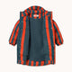 A children's puffer jacket with vertical orange-red and navy blue stripes, shown flat against a light cream background. The brand name 'TINY' is visible on the inner neck label.