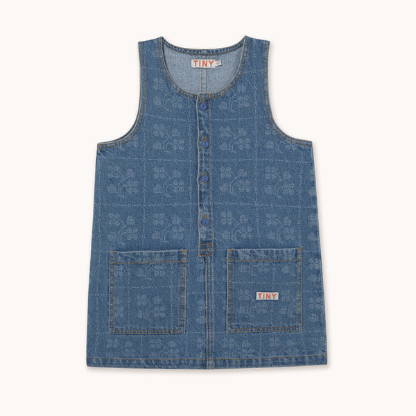 A sleeveless blue denim vest with a subtle tonal monogram pattern, featuring a button-up front and two front patch pockets, shown flat on a light cream background.