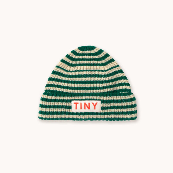 A green and cream striped knit beanie hat with a small white rectangular patch on the front that reads 'TINY' in red letters, shown against a plain off-white background.