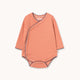 A baby long-sleeve wrap bodysuit with horizontal orange and white stripes, featuring a snap closure at the shoulder and a small brand label at the collar.