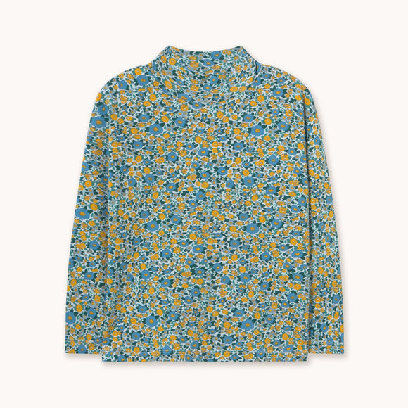 A long-sleeve mock neck shirt with an all-over dense floral print in blue, yellow, and green, displayed flat against a light off-white background.