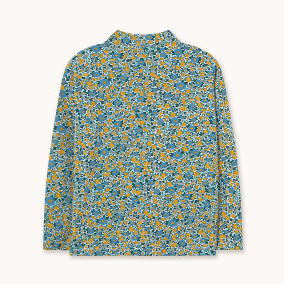 A long-sleeve mock neck shirt with an all-over dense floral print in blue, yellow, and white, displayed flat against a light off-white background.