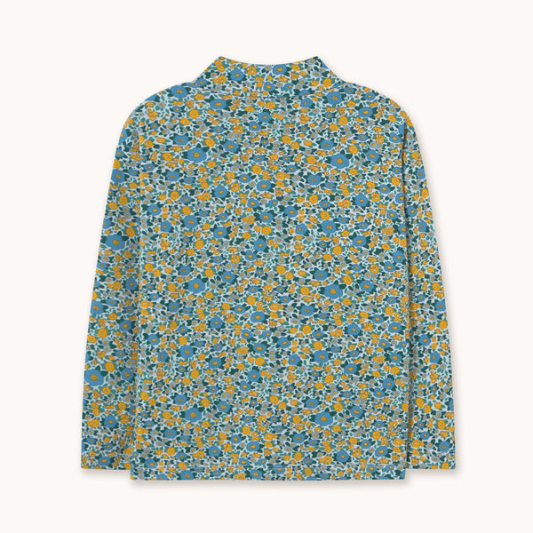 A long-sleeve mock neck shirt with an all-over dense floral print in blue, yellow, and white, displayed flat against a light off-white background.
