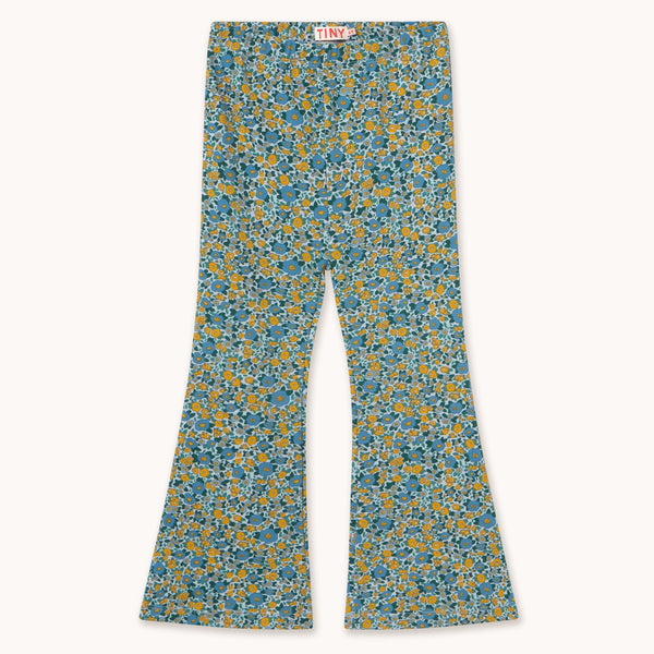 A pair of wide-leg pants featuring a dense blue and yellow floral pattern on a light teal base, laid flat against a light cream background.