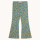 A pair of wide-leg pants featuring a dense blue and yellow floral pattern on a light teal base, laid flat against a light cream background.