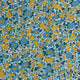 Close-up of a patterned garment or fabric panel with a dense floral print in blue, teal, yellow, and white. A small sewn label at the top reads TINY.