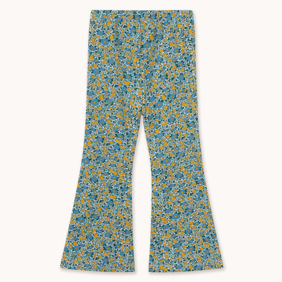 A pair of wide-leg pants featuring an all-over dense floral print in teal blue, yellow, and white, displayed flat against a light cream background.