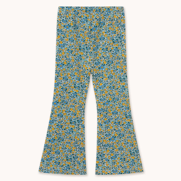 A pair of wide-leg pants featuring an all-over dense floral print in teal blue, yellow, and white, displayed flat against a light cream background.