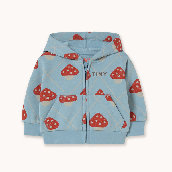 A light blue zip-up hoodie for kids, featuring an all-over print of red and white mushrooms, with the brand name 'TINY' printed on the chest, displayed against a solid off-white background.