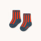 A pair of navy blue baby socks with bright orange vertical stripes and 'TINY' printed in orange on the cuff and sole, displayed on a clean off-white background.