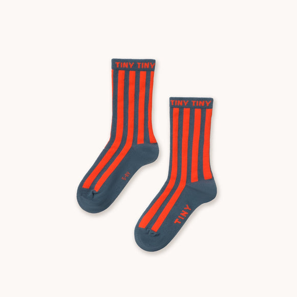 A pair of crew socks with vertical orange-red stripes on a dark navy blue base, shown on a plain off-white background.