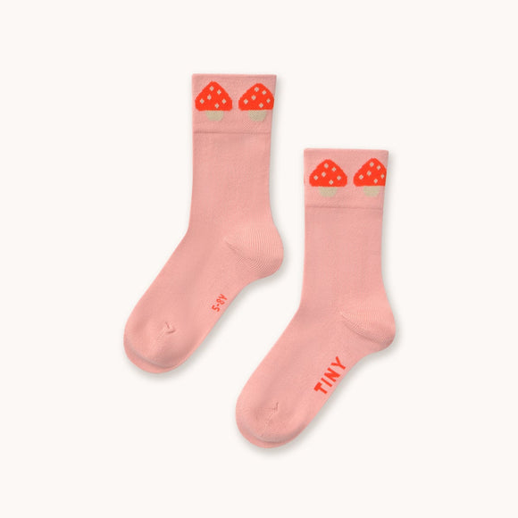 A pair of light pink crew socks with red strawberry graphics at the top and the brand name 'TINY' printed on the sole, displayed on a clean off-white background.