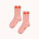 A pair of light pink crew socks with red strawberry graphics at the top and the brand name 'TINY' printed on the sole, displayed on a clean off-white background.