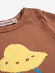 Close-up of a brown children's long-sleeve top with a yellow pixelated cloud graphic and a visible neck label reading 'CHOSES'.