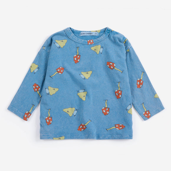 A light blue long-sleeve children's top with an all-over print of red mushrooms and yellow birds, displayed flat against a light gray background.