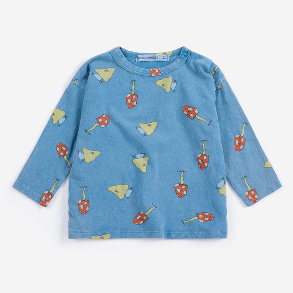 A light blue long-sleeve children's top with an all-over print of red mushrooms and yellow birds, displayed flat against a light gray background.