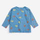 A light blue long-sleeve children's top with an all-over print of red mushrooms and yellow birds, displayed flat against a light gray background.