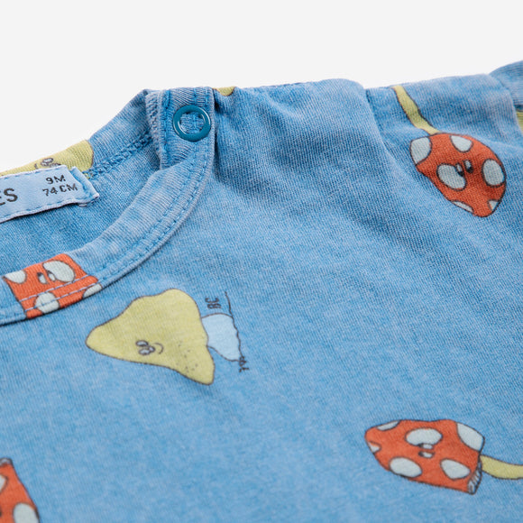 Close-up of blue fabric with cartoon mushroom patterns and a button.