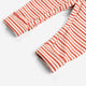 Close-up of a striped garment, likely a baby romper or pants, featuring alternating red-orange and cream horizontal stripes with a buttoned cuffed sleeve.