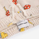 Close-up of a cream-colored children's sweatshirt with a colorful mushroom and giraffe print, featuring white drawstrings and a visible 'BOBO CHOSES' brand label.