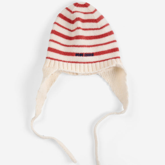 A cream-colored knit baby beanie hat with red horizontal stripes and matching tie straps, shown against a plain white background.
