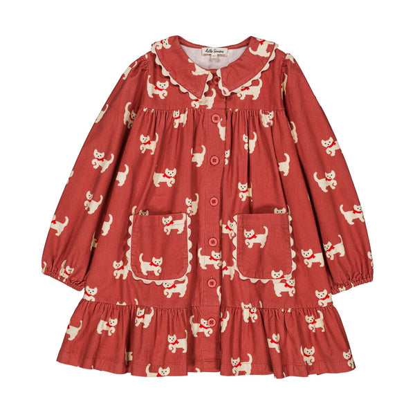 A toddler's long-sleeve button-up dress in a rust red fabric with a white cat print, featuring a Peter Pan collar, ruffled trim, and front pockets.