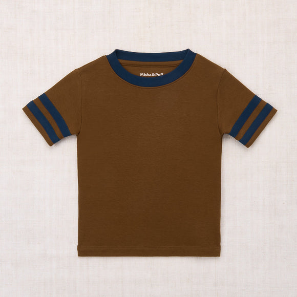 Brown t-shirt with blue stripes on sleeves and collar against a beige background