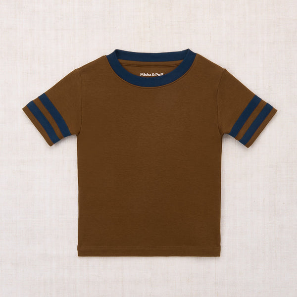 Brown t-shirt with blue stripes on sleeves and collar against a beige background