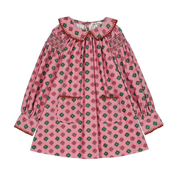 A pink long-sleeve blouse with a green and red floral pattern, featuring smocked detailing on the collar and cuffs, and decorative red piping.