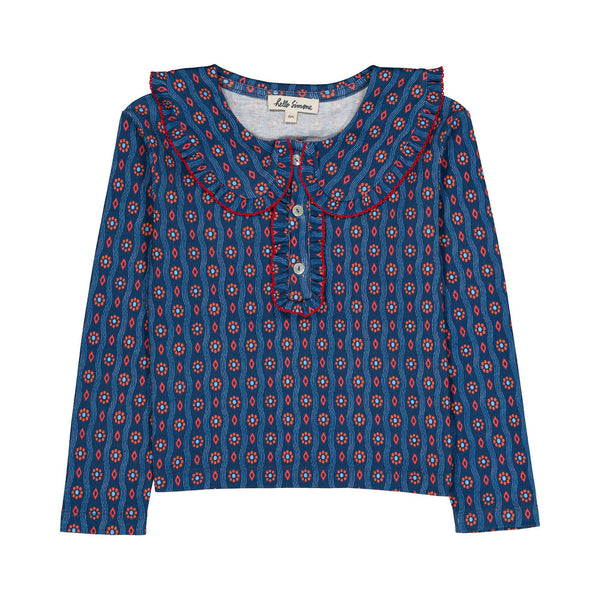 A long-sleeve top for kids by Hello Simone, featuring a blue base with a red and white geometric pattern, a ruffled collar, and a ruffled placket with red piping.