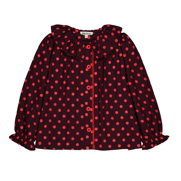 A long-sleeve blouse with a red and black polka dot pattern, featuring a ruffled collar, button-up front, and ruffled cuffs, shown flat on a white background.