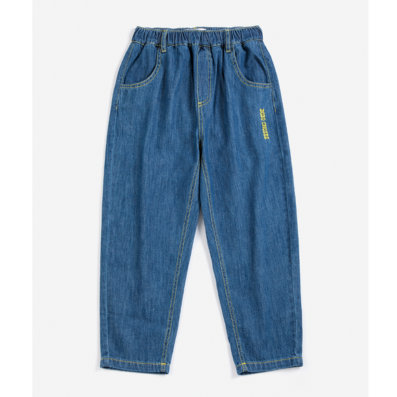 A pair of children's blue denim pants with an elastic waistband, side pockets, and a small yellow embroidered logo on the left thigh, shown against a plain light background.
