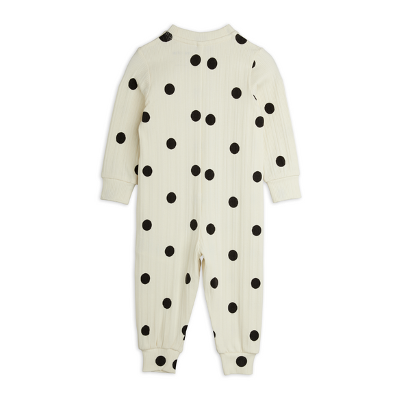 A cream-colored ribbed baby jumpsuit with black polka dots, shown from the back on a plain white background.