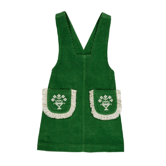 A green corduroy pinafore apron with two front pockets featuring white embroidered floral designs and white lace trim, shown flat on a white background.
