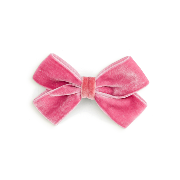 A small pink velvet bow accessory, likely for a dog collar or costume, centered on a plain white background.