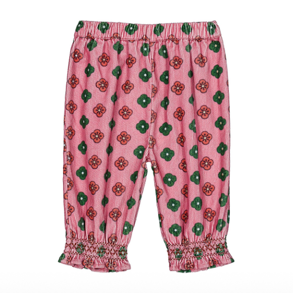 Pink children's pants with an allover green and red floral pattern, featuring an elastic waistband and smocked ruffled cuffs at the ankles.
