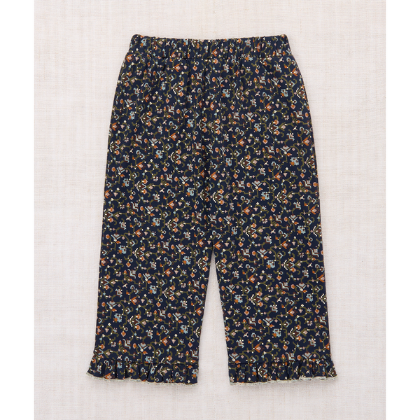 A pair of cropped pants with an all-over small floral print on a dark navy background, laid flat on a light beige textured fabric background.