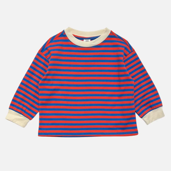 A children's long-sleeve striped top with horizontal red and blue stripes, featuring a cream crew neck and cuffs, shown flat against a light gray background.