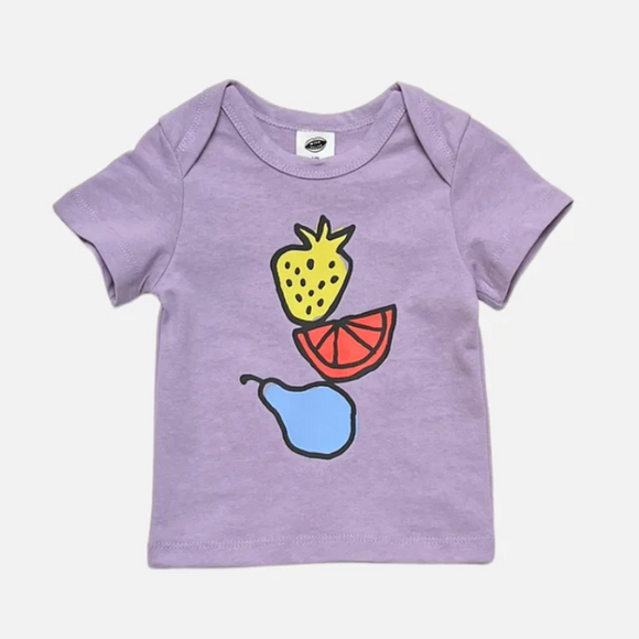 A baby short-sleeve t-shirt in light purple, featuring a colorful graphic print of a yellow pineapple, a red grapefruit slice, and a blue pear on the front, set against a plain light gray background.
