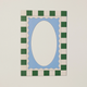 A square decorative frame or mat design with a green and cream checkered border surrounding a light blue scalloped inner border and a large cream oval center, shown on a plain light background.