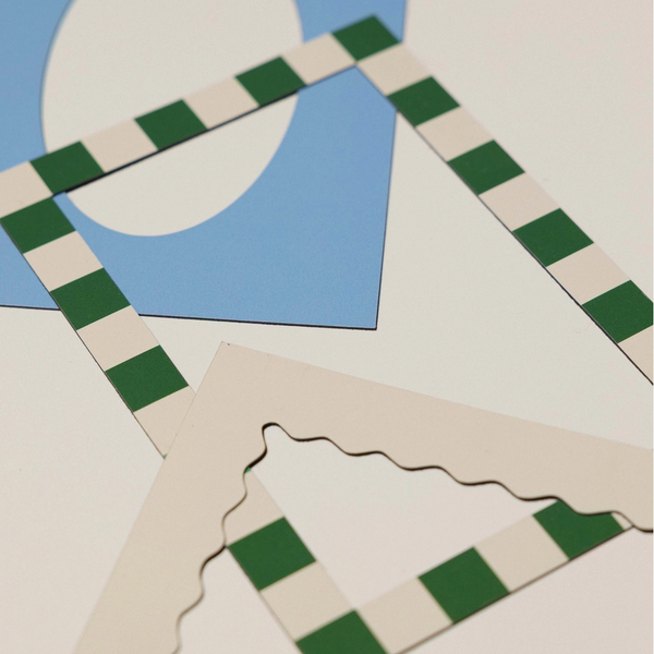 A close-up of layered paper craft templates or frames, featuring green and white checkered borders, cream-colored scalloped edges, and a blue geometric shape on a white background.