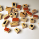 A set of small wooden rubber stamp blocks scattered on a white surface, each featuring different engraved or stamped botanical and abstract designs in black and reddish-brown.
